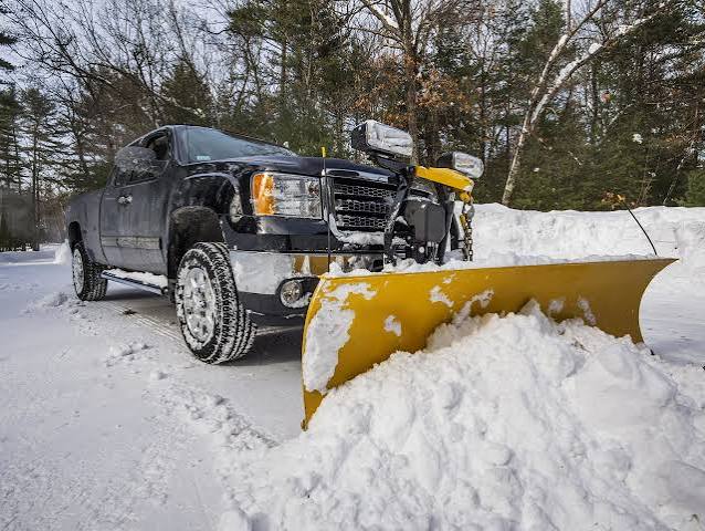 Truck with snow plow clearing a driveway